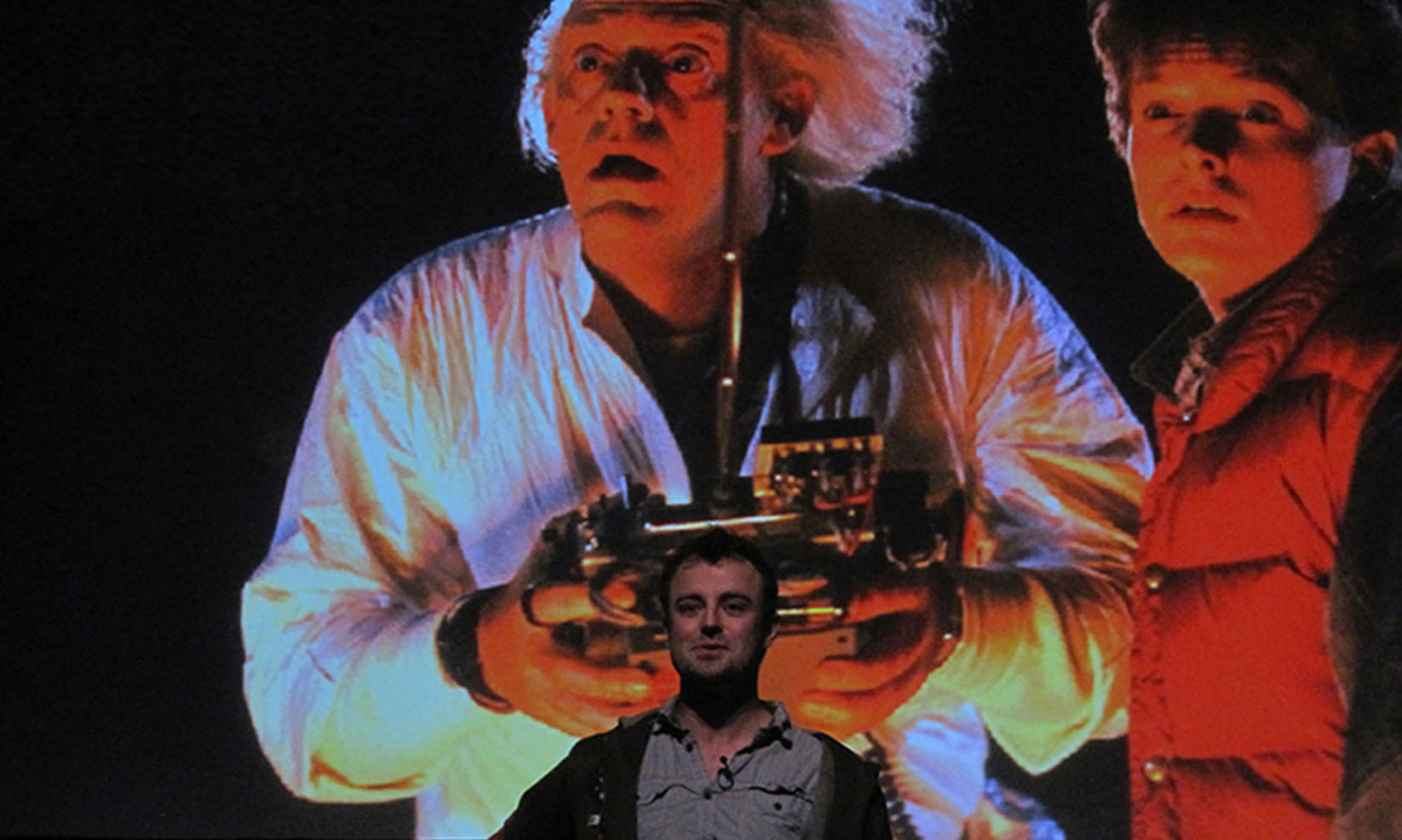 Fabian Hemmert, giving a presentation in front of a 'Back to the Future' movie still.